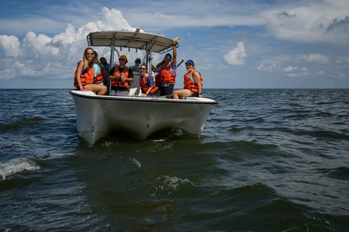 rear view of many people in life jackets on an open boat in the open water