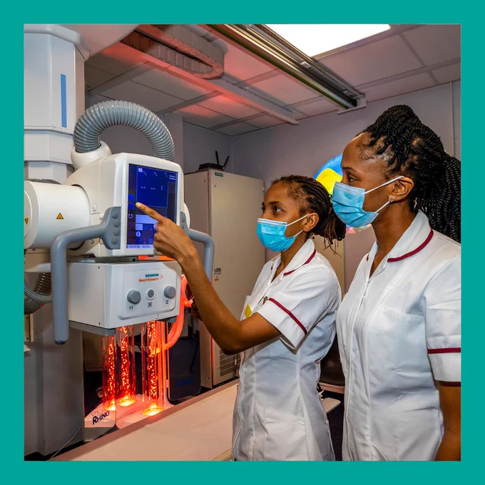 Two Radiographers interacting with a Radiography machine
