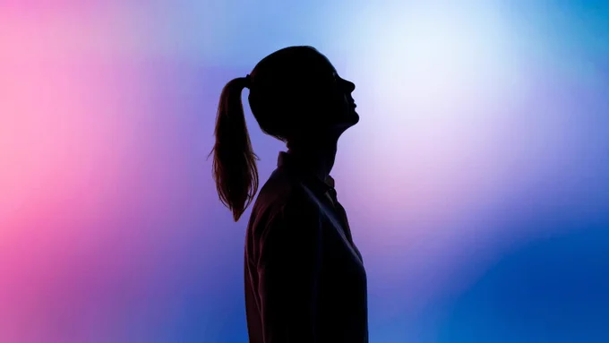 A person is shown here in silhouette, standing in profile against a pink and blue background.