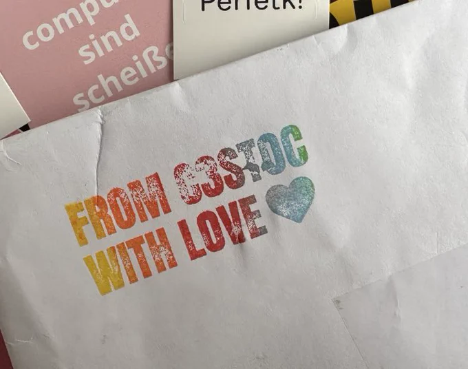 A white envelop with a rainbow stamp that says “from c3stoc with love” followed by a heart