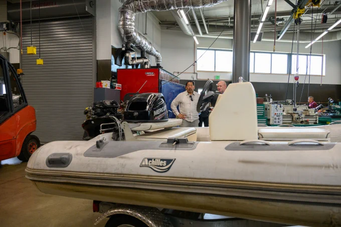 A small boat in the foreground, as Mayor Harrell listens to a Seattle Maritime Academy representative.