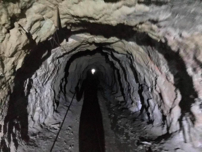 Woman wearing headlamp pointed down a mine shaft