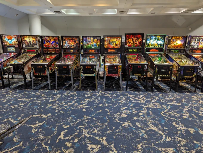 
A row of pinball machines including Rush, Game of Thrones, Black Knight 2000, Theater of Magic, World Cup Soccer, NBA Fast Break, Guns & Roses, Godzilla (Sega), Big Buck Hunter, and Transformers. 