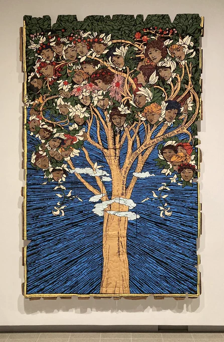 A print of a tree set against a blue background with women’s faces depicted in the branches. The words “We are part of nature, not outside of it. What we do to Earth we do to ourselves” run along one branch.