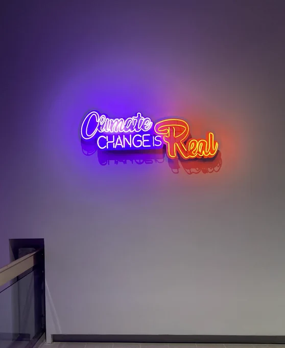 A neon sign reading “Climate change is real”