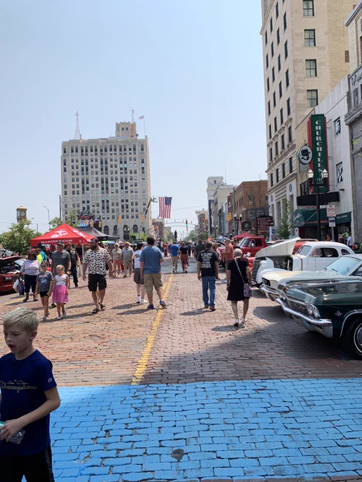 Brick street lined with vintage cars and spectators