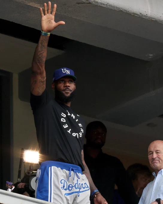 LeBron James waves to the crowd at Dodger Stadium. He wears an Uninterrupted t-shirt with Dodgers shorts.