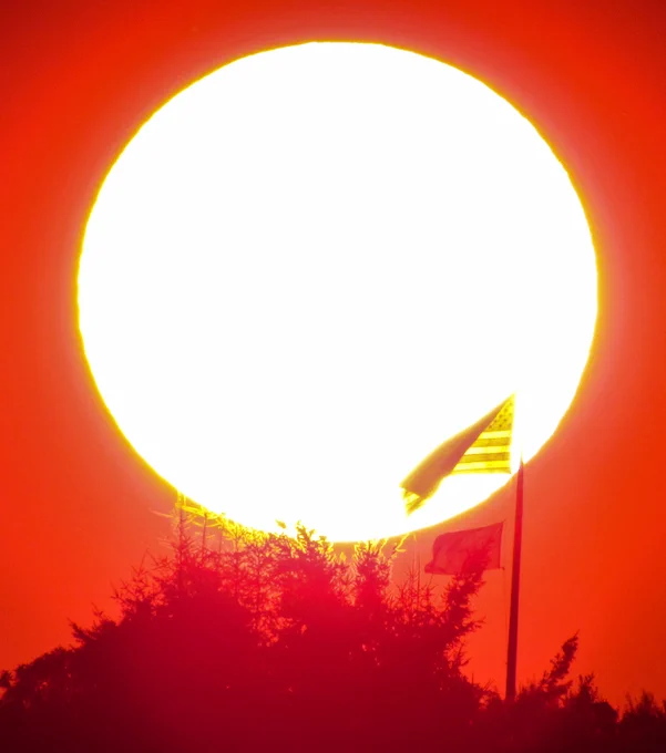 A very red sunset at NWS Seattle with the outline of a distant American flag in front of the Sun.