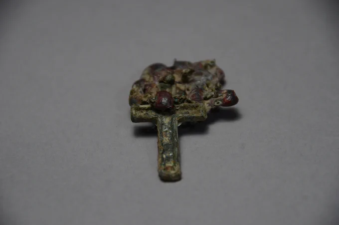Picture of a melted crucifix that was unearthed during construction of a house in Nagasaki. It is photographed on a gray background.