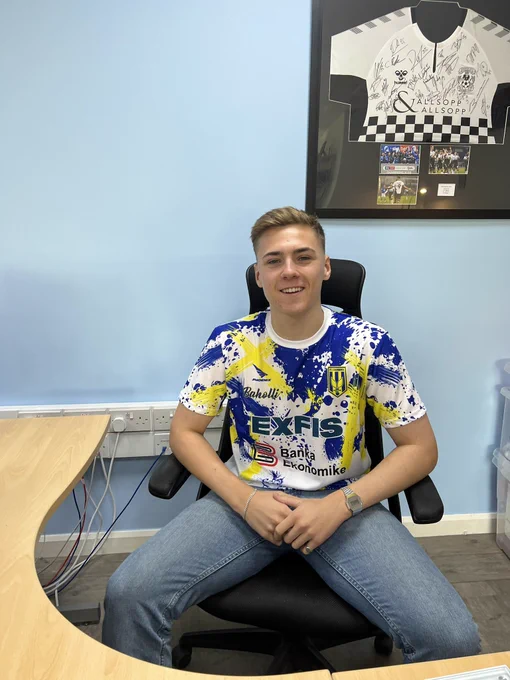 Louis sat at his desk, wearing one of the latest arrivals - the KF 2 Korriku away shirt, a white design with yellow paint strokes and navy blue paint splatters all over.