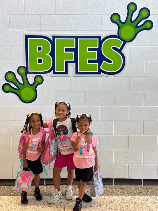 Three students pose for a picture under a sign that says "BFES."
