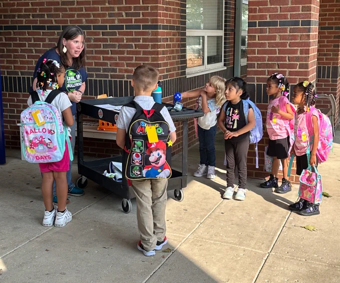 A staff member talks to six students outside.