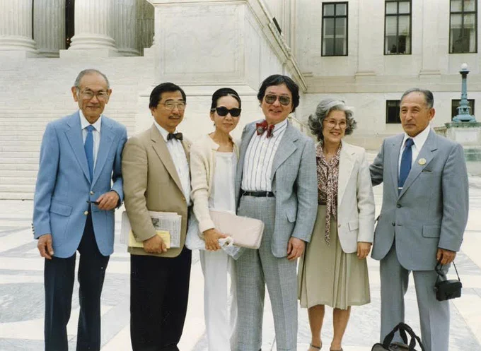 Photograph of Fred Korematsu, Gordon Hirabayashi, Michi Weglyn, William Hohri, Aiko Herzig Yoshinaga, and Harry Uyeno standing together in front of the Supreme Court building.