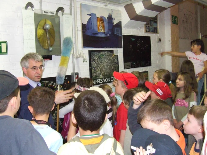 Schüler folgen während einer Führung im Planetarium gespannt der Erklärung und Demonstration der Keplerbewegung eines Planeten.