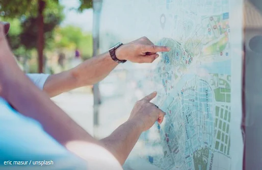 Hände und Finger zeigen auf einen Stadtplan. Bildnachweis: eric masur / unsplash