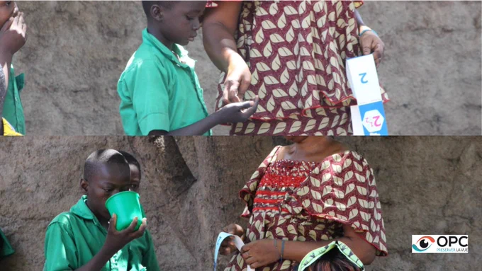 Images représentant une distribution de médicaments aux enfants tchadiens lors du programme Givewell pour combattre les maladies tropicales négligées les schistosomiasis et les géohelminthiases. Une enseignante tchadienne donne le médicament à l'enfant et l'enfant boit ensuite de l'eau pour bien avaler le médicament. 
