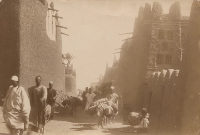 street view, with buildings lining the sides and people passing along the street