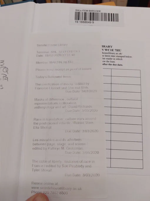 a photo of an open book with a receipt in it. the books on the borrowed items list are: The creolization of theory, Masks of difference, Race in translation, Les Miserables and its afterlives, and The color of liberty. 