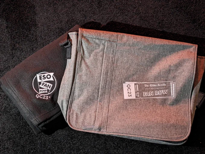 A gray ESO messenger bag and fuzzy black blanket rest on the QuakeCon stage.