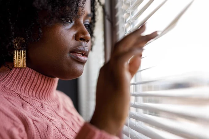 Woman looking through blinds