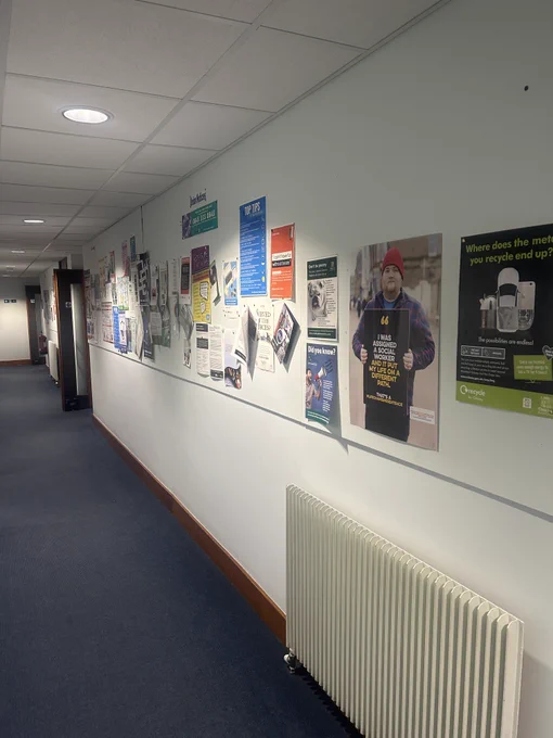 A corridor with lots of posters on the wall, including a Life Changing Sentence poster with the text 'I was assigned a social work and it put my life on a different path'