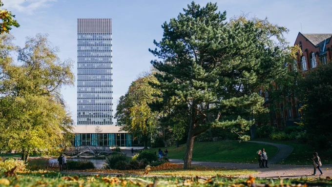 The University of Sheffield Arts Tower framed by trees of Weston Park, people walking in foreground.