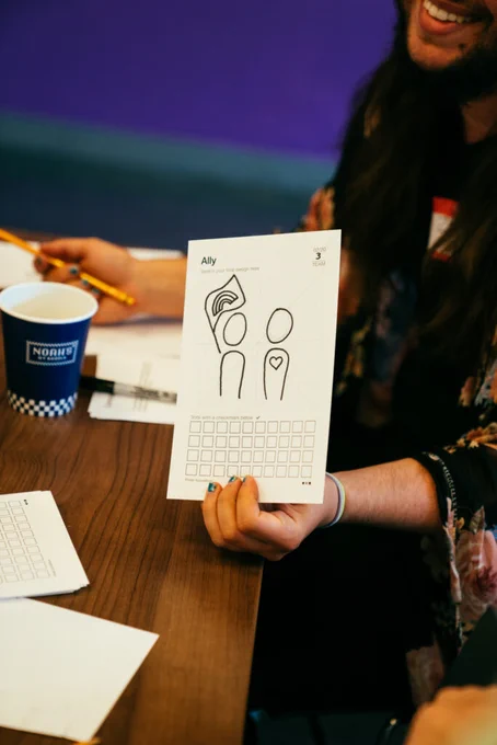 Photo of a person holding up a sketch for a new icon depicting the term "Ally"