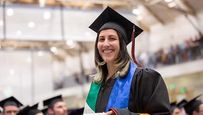 Virginia wearing a graduation cap and gown smiling at the camera