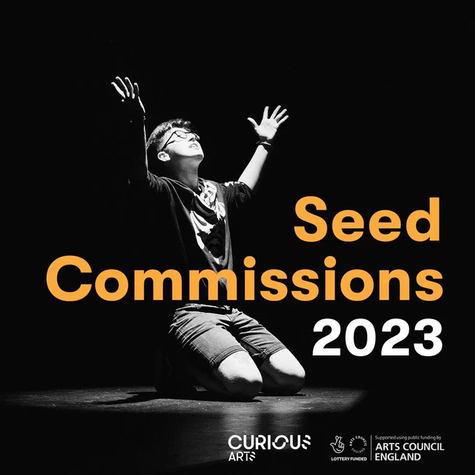 A monochrome image of Mack Sproates, Curious Arts' supported artist 2019, on stage under a spotlight on their knees, looking up with their arms in the air. They have short hair and wear glasses, a t-shirt and denim shorts. Over the image is text that reads "Seed Commissions 2023". At the bottom are the Curious Arts and Arts Council England logos.
