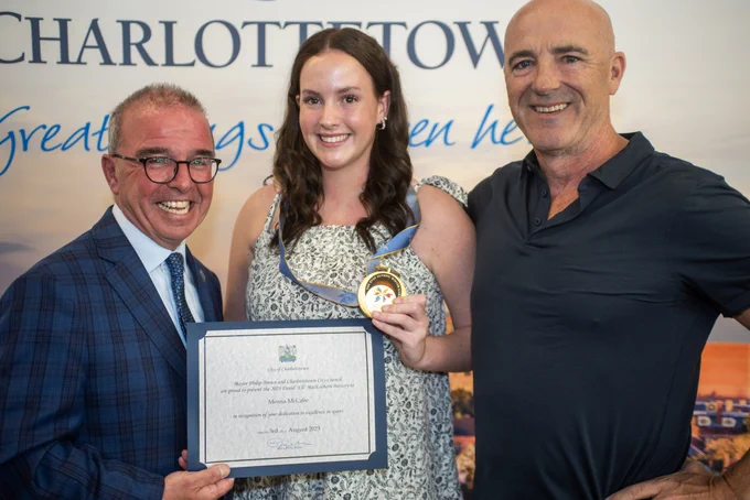 Mayor Philip Brown poses with Menna McCabe and a third person. Menna is holding her David ‘Eli’ MacEachern Bursary medal. The Mayor is holding a certificate.