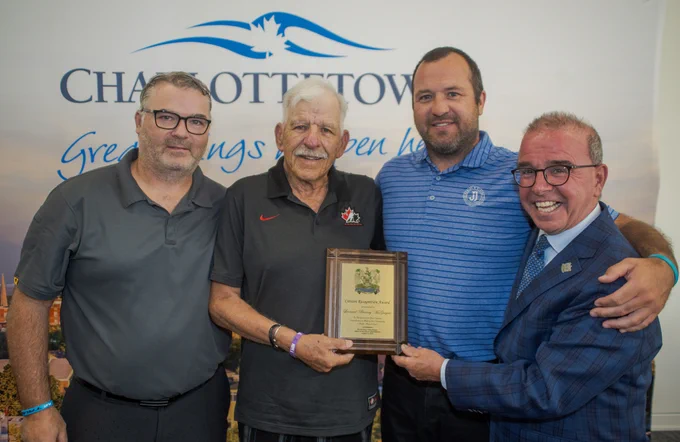 Mayor Philip Brown and three men pose for the camera, with a Citizen’s Recognition Award. 