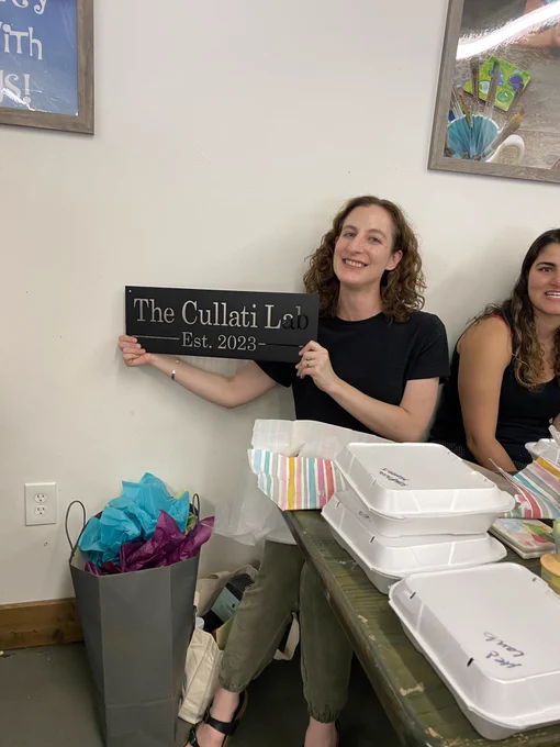 Sierra holds a sign that reads “The Cullati Lab, established 2023” which was a gift from her labmates.