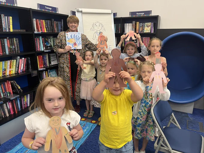 Children smiling and holding up their swimmers with illustrator Sharon Davey after a fun workshop