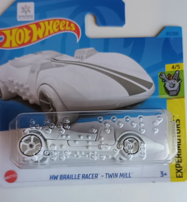 A Hot Wheels Twin Mill toy car in the package. It is fully white and there is Braille writing on the package plastic and on the car where there would be decals and text.