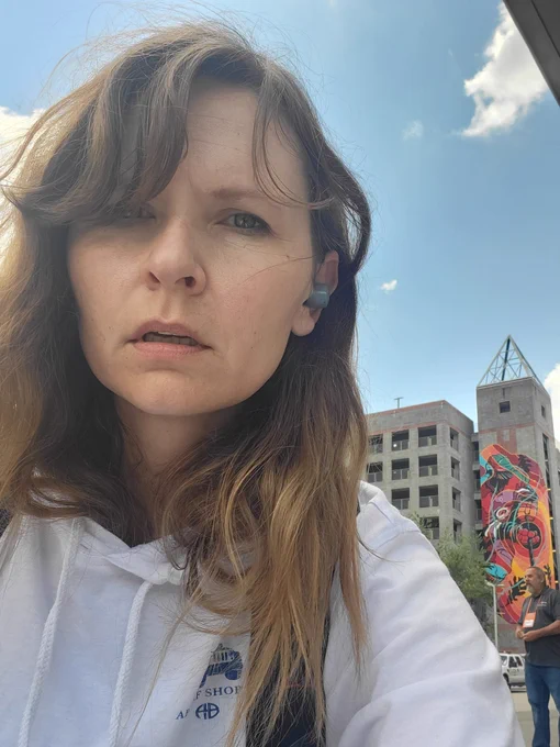 White woman looking exhausted in downtown Raleigh with buildings behind 