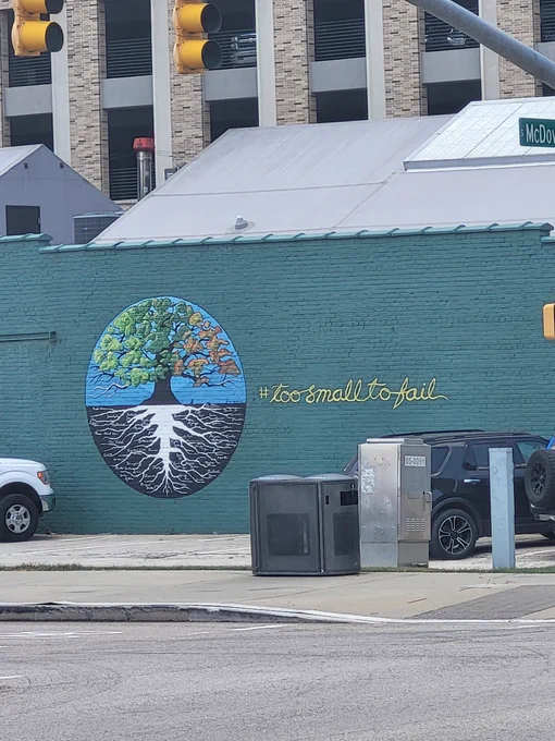 Mural on the side of a building with the world tree and the hashtag too small to fail
