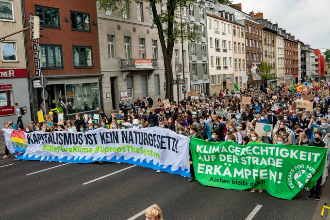 zu sehen ist eine FFF Demonstration in Aachen mit 2 Bannern "Kapitalismus ist kein Naturgesetz" und "Klimagerechtigkeit auf der Straße erkämpfen"