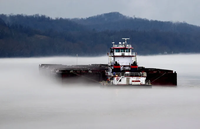 Barge and tugboat on misty river.