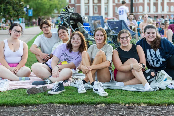 A group of students sit on blankets.