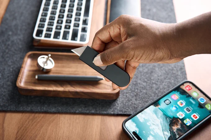 A hand holding a Keen, extending the blade with the slider on the side.