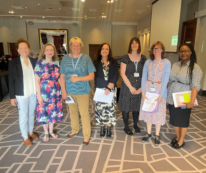 Female staff members from NWAS and other North West NHS trusts at one of the hospital handover collaborative events smiling at the camera. 