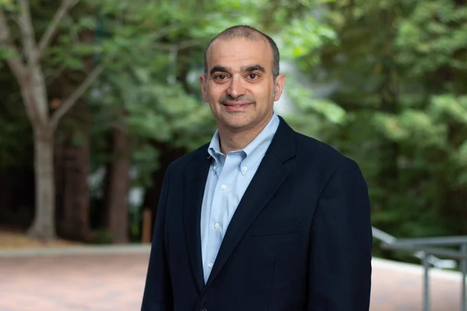 portrait of Bryan Gaensler in a suit jacket smiling at the camera with trees in the background