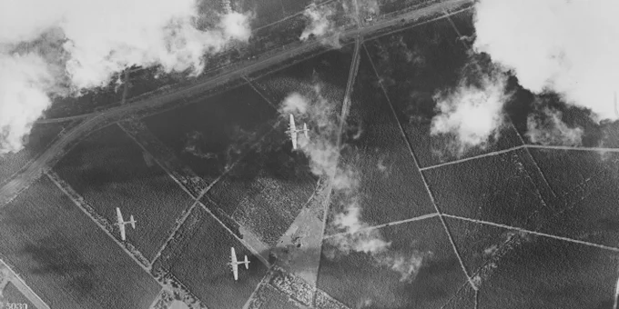 A black and white aerial photograph of planes flying over farmland.