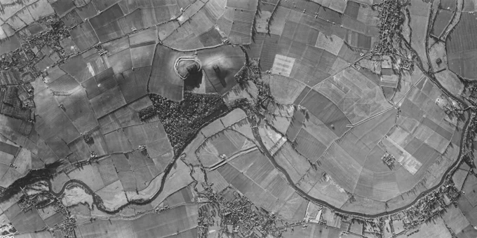 A black and white aerial photograph of farmland, small villages, and a river running through.