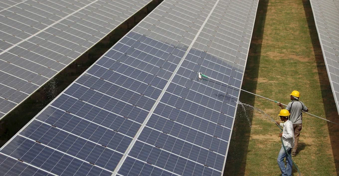 Workers clean photovoltaic panels inside a solar power plant in Gujarat, India. Credit: Reuters / Alamy Stock Photo.