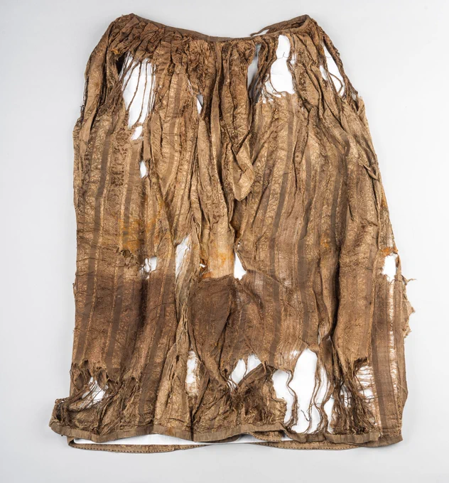 A petticoat, brown with age and with many holes. The pattern is still faintly visible.
