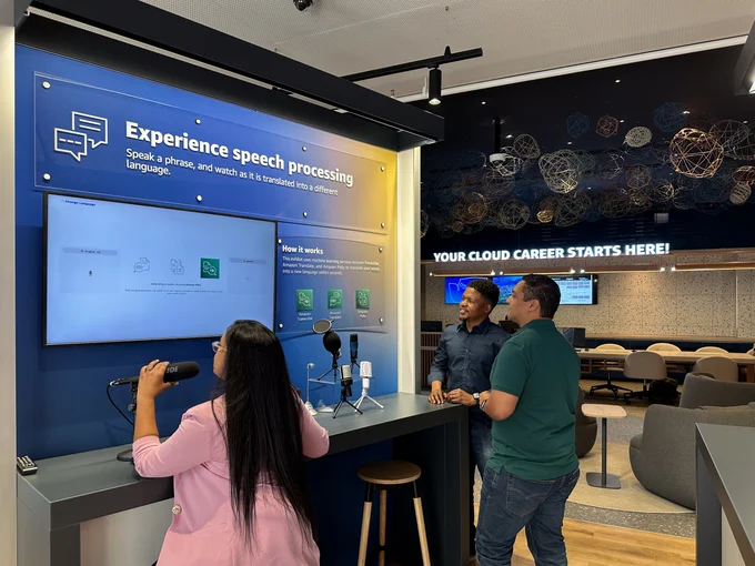 People looking at a sign that says, Experience speech processing.