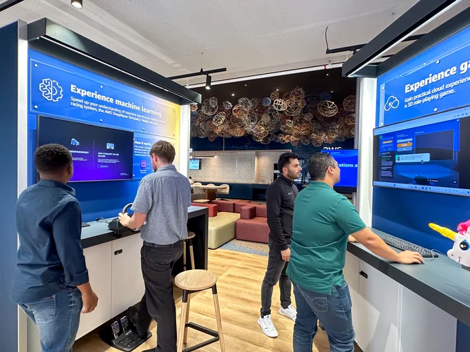 Individuals participating in the deep racer and cloud quest exhibits at the AWS Skills Center in Cape Town, South Africa.