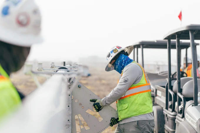 Two individuals in hard hats and high visibility vest installing solar trackers  
