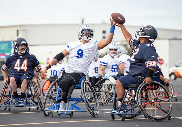 A Chicago Bears wheelchair football players goes up for the ball against a Dallas Cowboys wheelchair football player